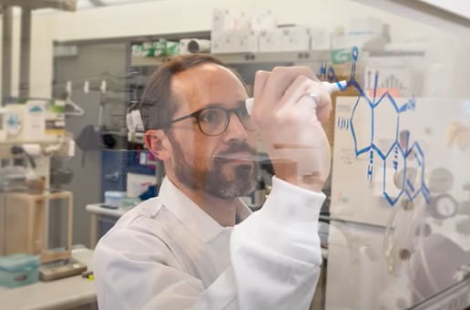 Un chercheur écrivant sur un tableau transparent