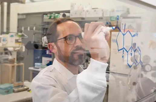 A researcher writing on a clear board