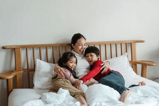 A mother hugging her two children in bed