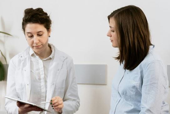 Un médecin et une patiente regardant un document sur une planchette à pince