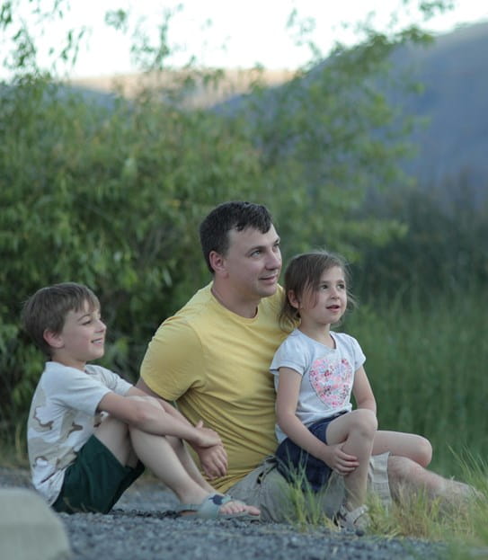 A father sitting in a field with his 3 children