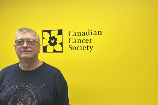 Doug Berry debout devant un mur comportant le logo de la jonquille et le nom de la Société canadienne du cancer