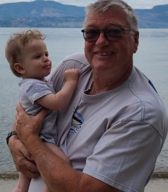 Doug Berry holding his grandchild on a beach