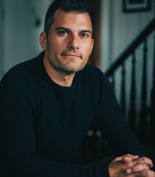 Portrait de Craig Savill, les mains jointes, regardant l'appareil photo.