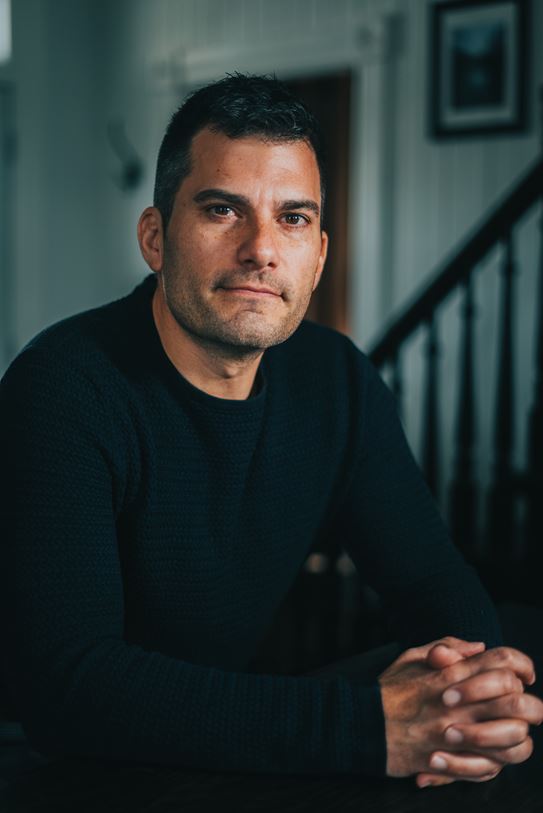 Portrait de Craig Savill, les mains jointes, regardant l'appareil photo.