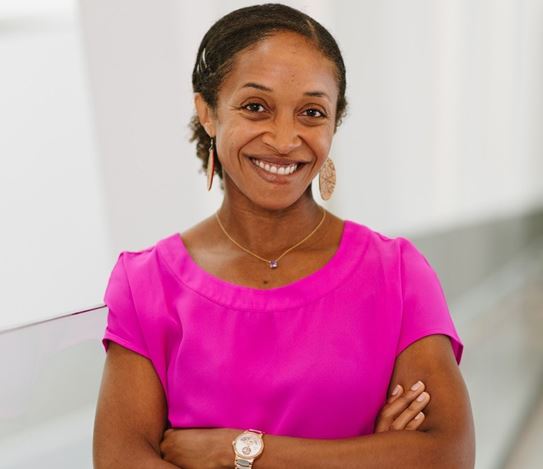 Dr Aisha Lofters smiling with her arms crossed.