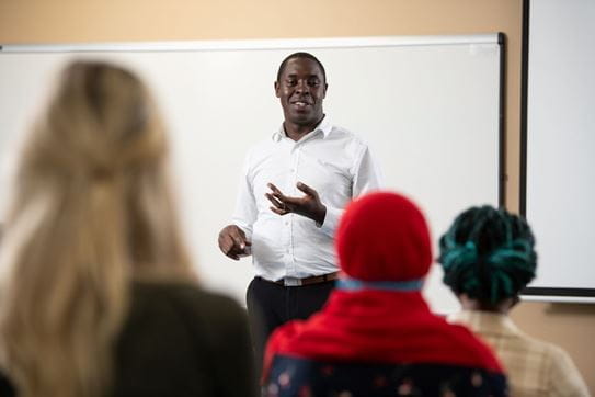 David Busolo, Ph. D., debout, devant un tableau blanc, faisant face à un groupe de personnes.