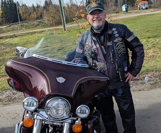 John Breen, photographié avec une moto devant un champ