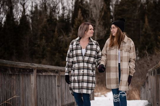 Renée and Ava walking on a wooden bridge in a park on a winter day