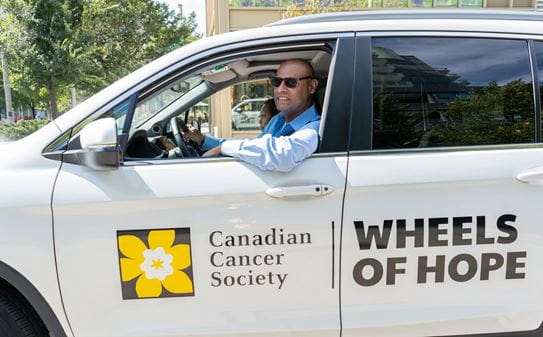 James looking at the driver’s window of a Wheels of Hope Honda. 