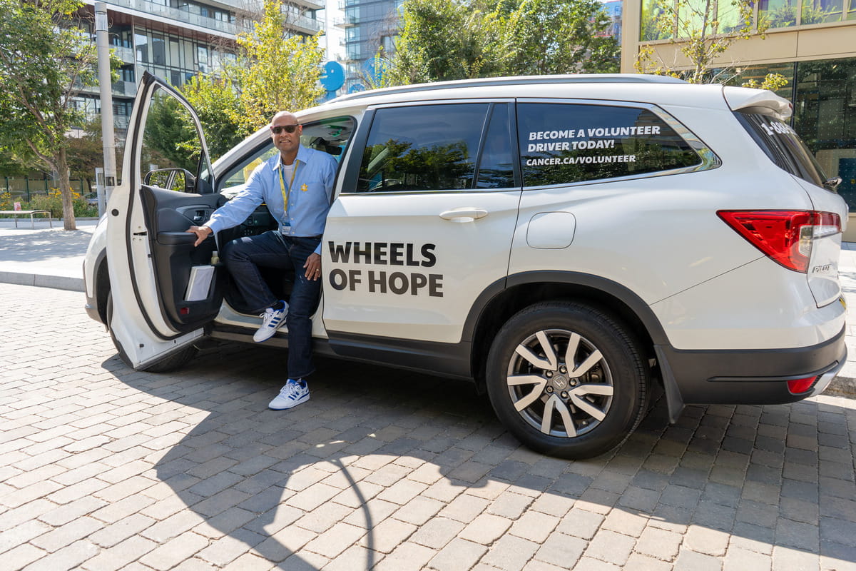 James sitting at the driver's seat of a Wheels of Hope car with the door open.