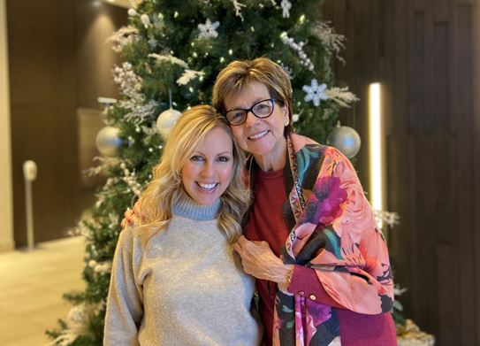 Emilie Cerretti and her mother standing in front of a Christmas tree