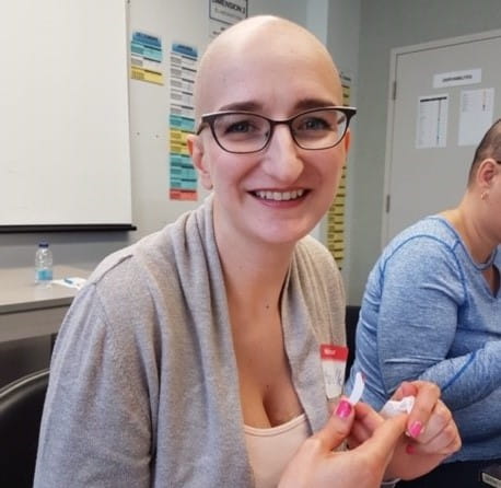 Marie-Noëlle, sans cheveux, souriant à la caméra