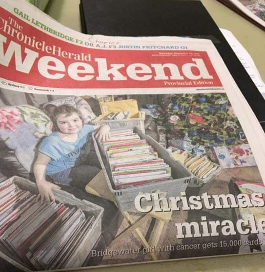 A newspaper article with a photo of Hailey with boxes of Christmas cards.