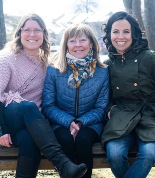 Louise-Hélène is sitting on a bench with her two daughters.
