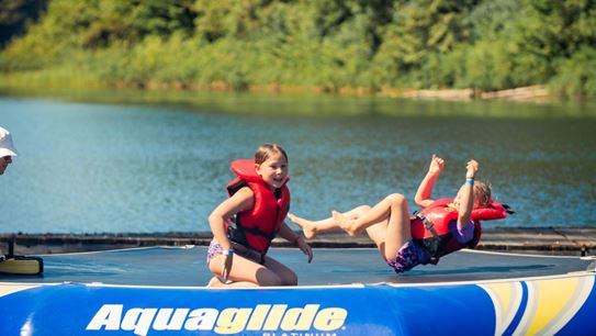 Paisley and Tenley playing on a trampoline in the lake