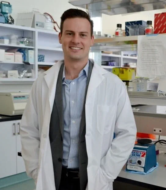 Dr Alexander Wyatt in his laboratory wearing a lab coat and smiling at the camera