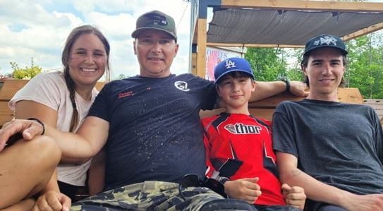 Sébastien sitting on a bench with his partner and his two sons