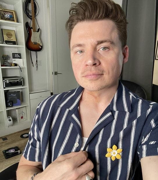 Shawn looking at the camera wearing a daffodil pin on his shirt