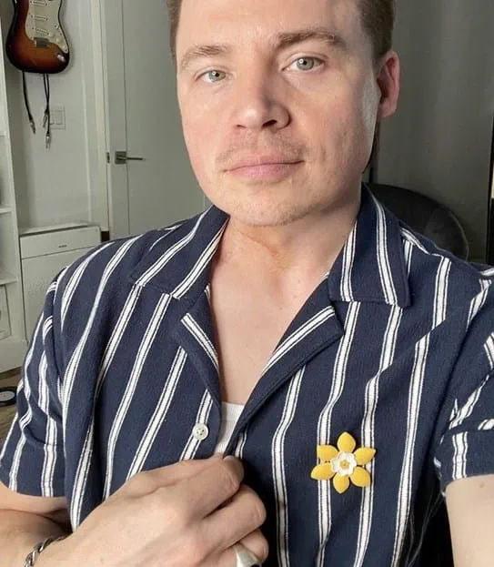 Shawn looking at the camera wearing a daffodil pin on his shirt