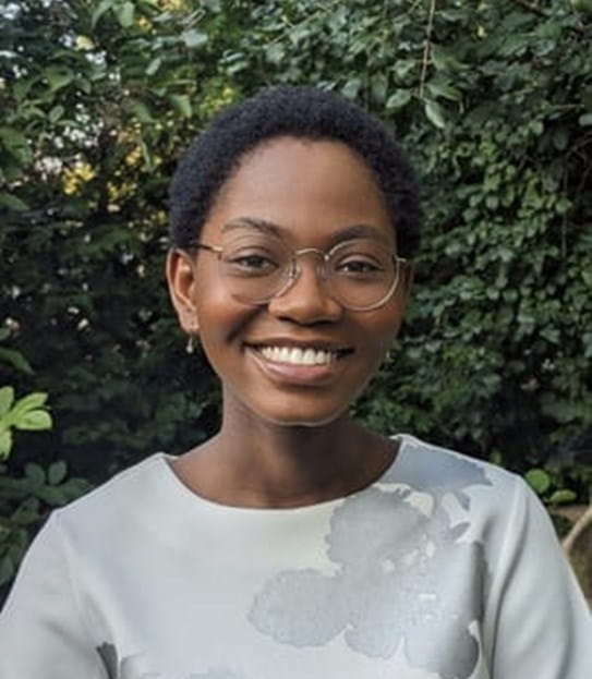 Chantel Mukonoweshuro in front of tall bushes.