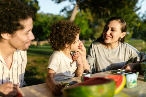 A child sitting at a table in between their smiling parents.