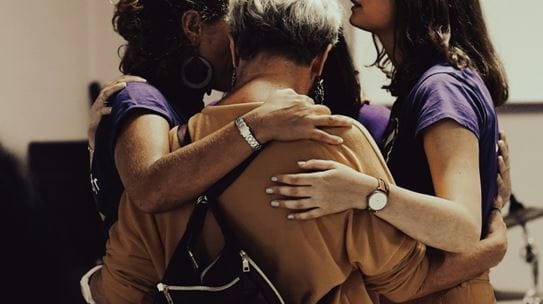 A group of people huddled together with their arms around each other.