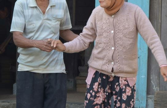 Deux personnes marchent ensemble. L’une tient le bras de l’autre.