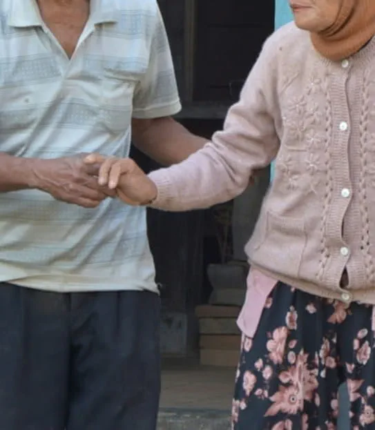 Deux personnes marchent ensemble. L’une tient le bras de l’autre.