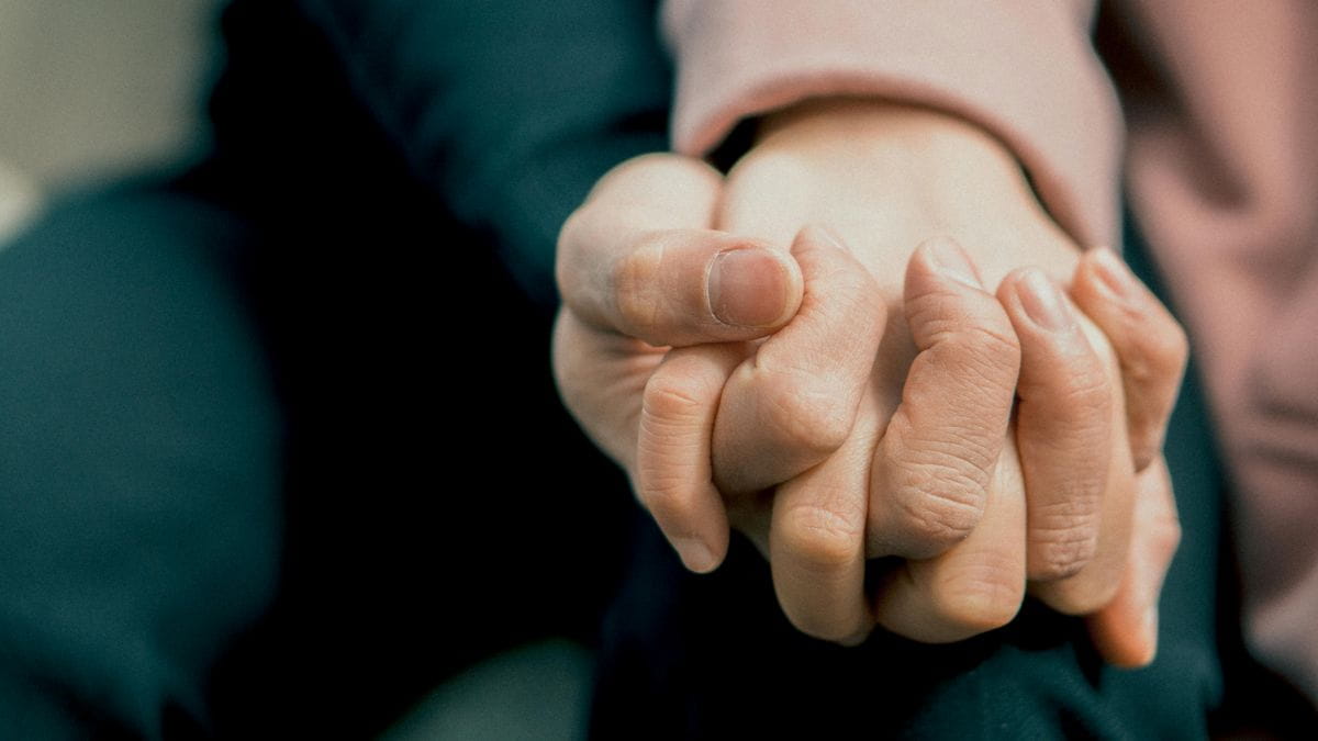 A close up of two people holding hands. 