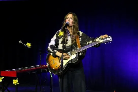 BEYRIES debout avec sa guitare une scène décorée de jonquilles