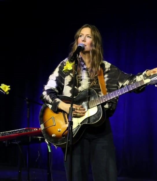 BEYRIES debout avec sa guitare une scène décorée de jonquilles