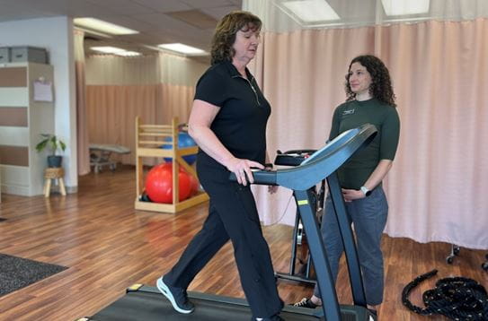 Terri Swain-Collins marche sur un tapis roulant pendant que sa physiothérapeute l’observe.