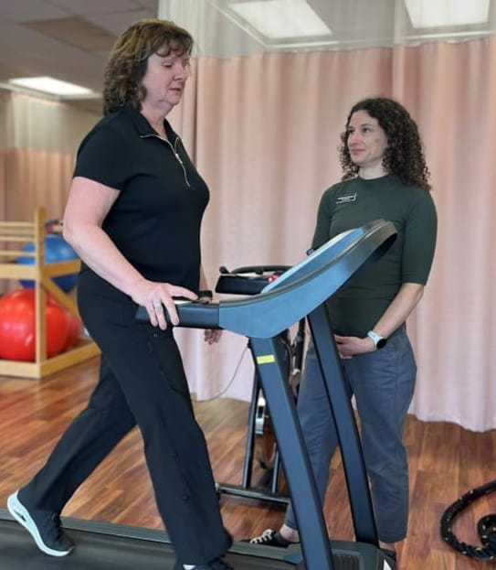 Terri Swain-Collins walking on a treadmill while her physiotherapist watches her.