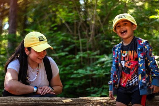 Two campers smiling in front of trees.