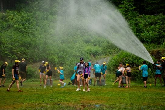 People playing under the water being sprayed from a hose.