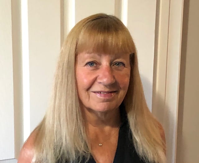 Gayle Archibald, souriant devant une porte.