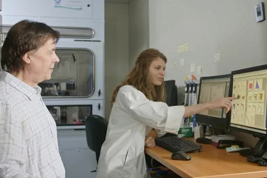 Deux chercheurs regardent un écran d’ordinateur dans un laboratoire. La chercheuse à droite pointe l’écran.