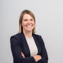 Dr Jennifer Croke smiling and standing in front of a wall with her arms crossed.
