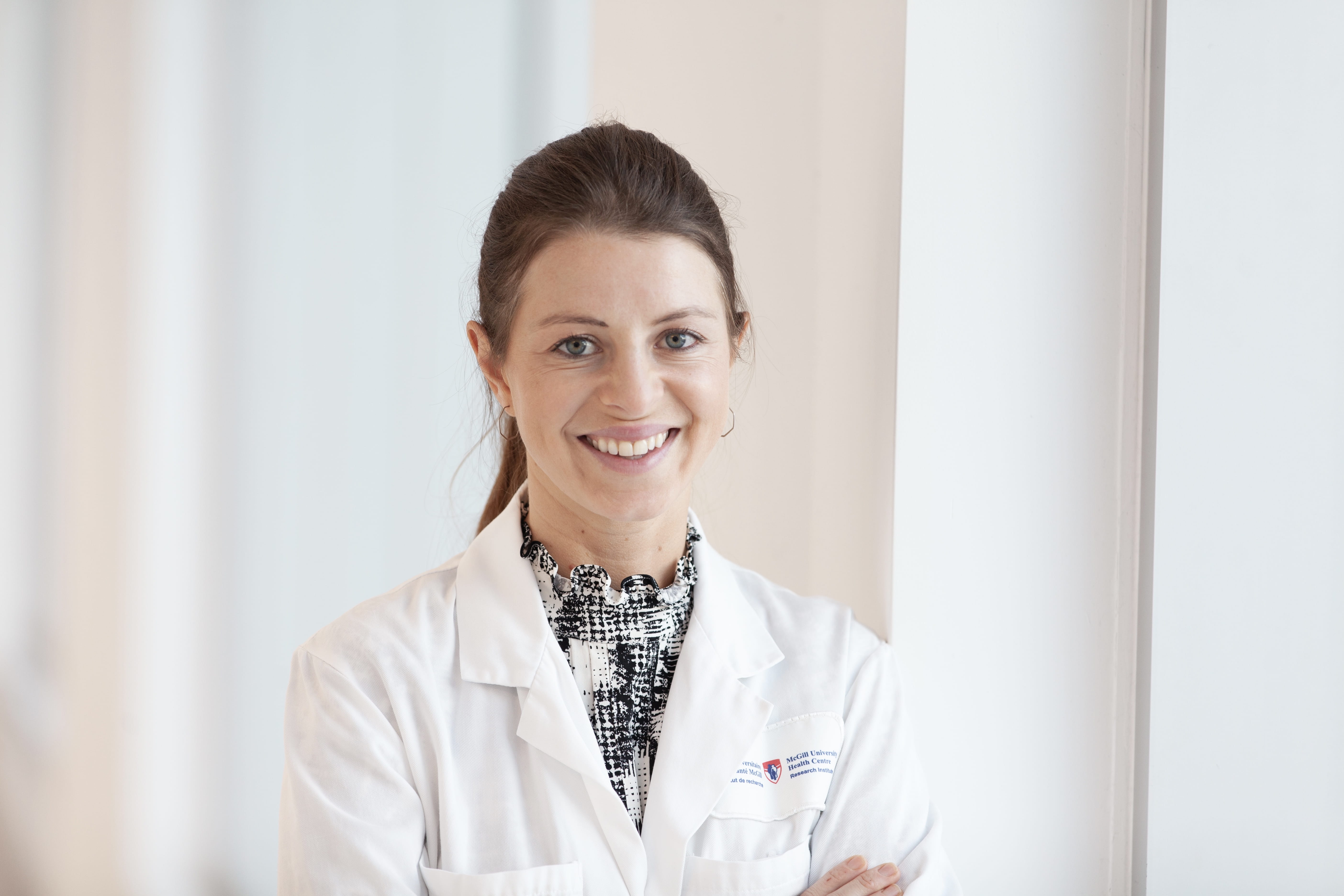 A headshot of researcher Dr Julia Burnier, who is wearing a McGill University lab coat.