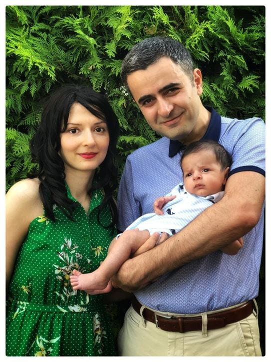 Salimeh standing next to her husband while he holds their son in his arms.