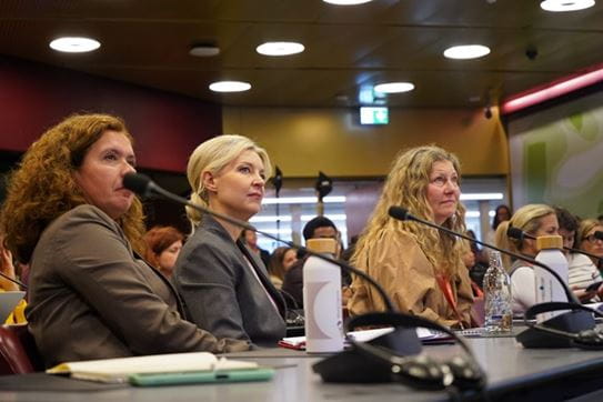 Kathy Andrews, assise entre deux collègues lors du Congrès mondial sur le cancer à Genève, en Suisse.