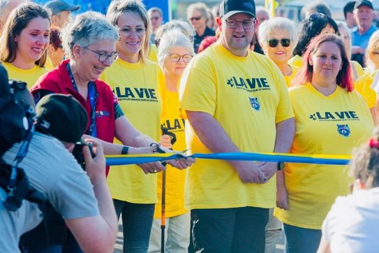 Jimmy Morel est debout derrière la ligne de départ, entourés de participants d’espoir en t-shirt jaune.
