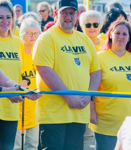 Jimmy Morel est debout derrière la ligne de départ, entourés de participants d’espoir en t-shirt jaune.