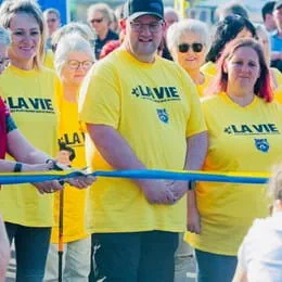 Jimmy Morel stands behind the Relay For Life starting line, surrounded by participants in yellow t-shirts.