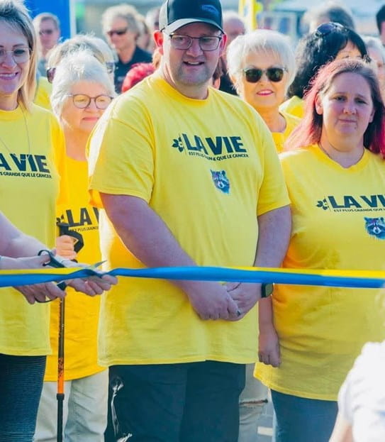 Jimmy Morel stands behind the Relay For Life starting line, surrounded by participants in yellow t-shirts.