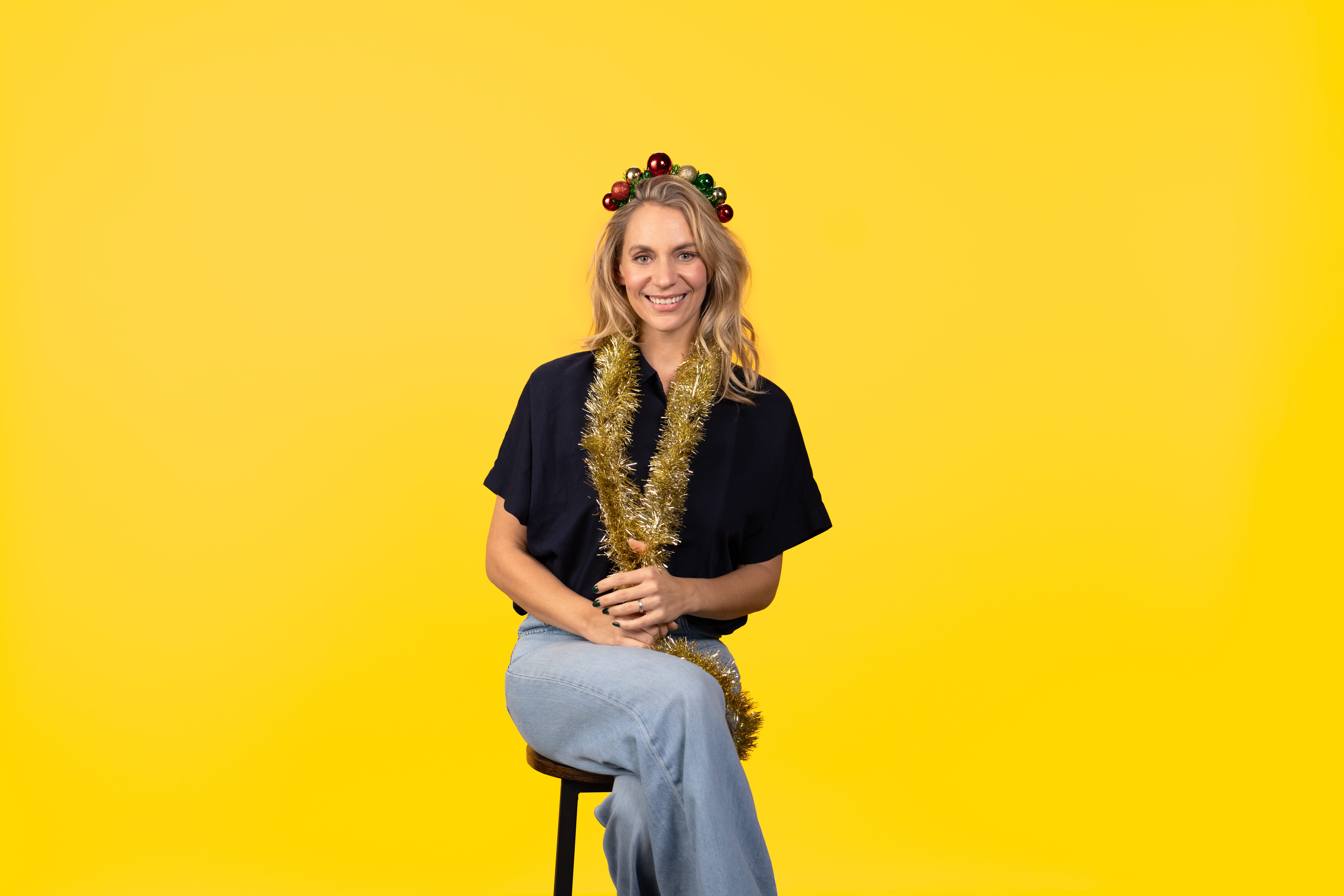 Léane Labrèche-Dor assise sur un tabouret avec une guirlande festive autour du cou.
