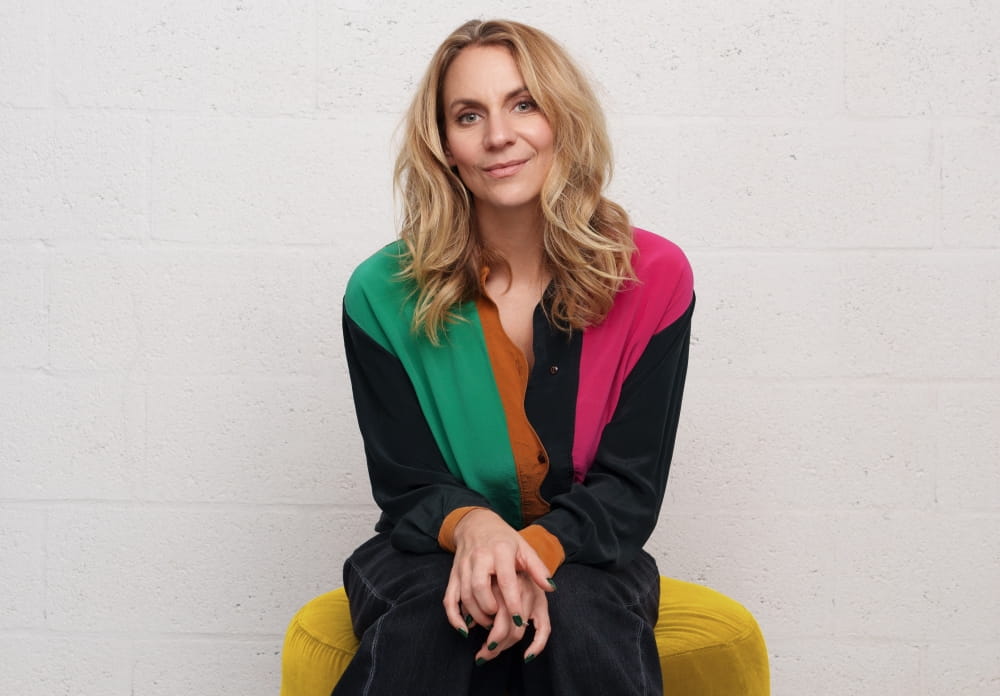 Léane Labrèche-Dor, souriante et assise sur un fauteuil jaune. 