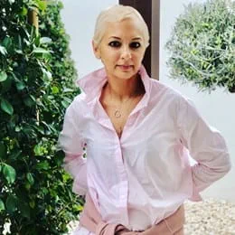 Nalini Sharma standing in front of a tree with her arms behind her back.