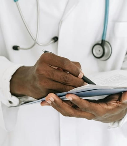 Un médecin portant un stéthoscope et un sarrau de laboratoire écrit sur un graphique.